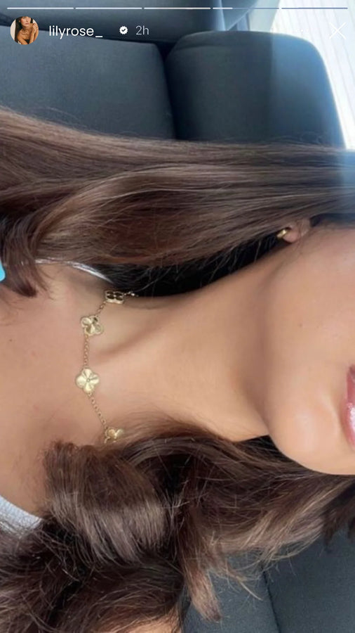 Layered clover necklace and gold jewelry on a brunette