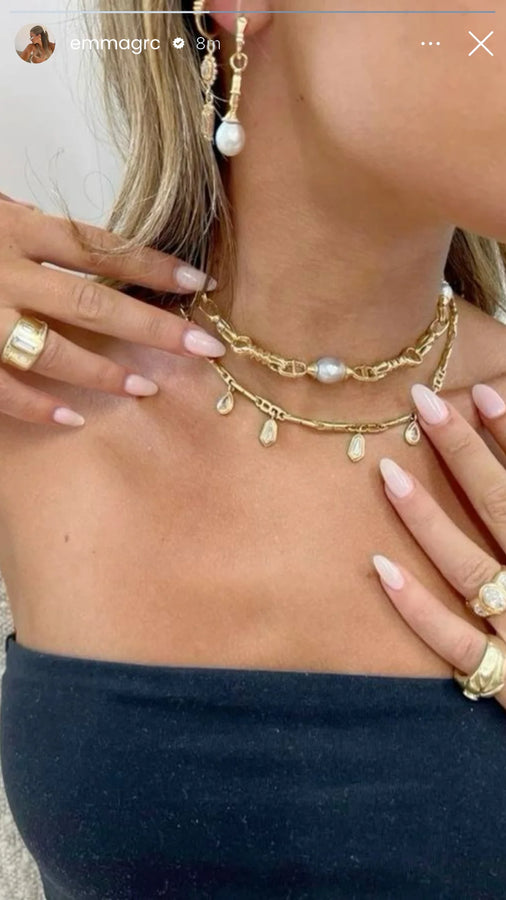 Gold necklace and pearl drop earrings styled on a black top